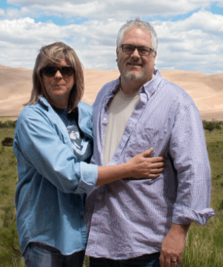 Patients Joe and Becky L. standing in front of sand dunes and smiling